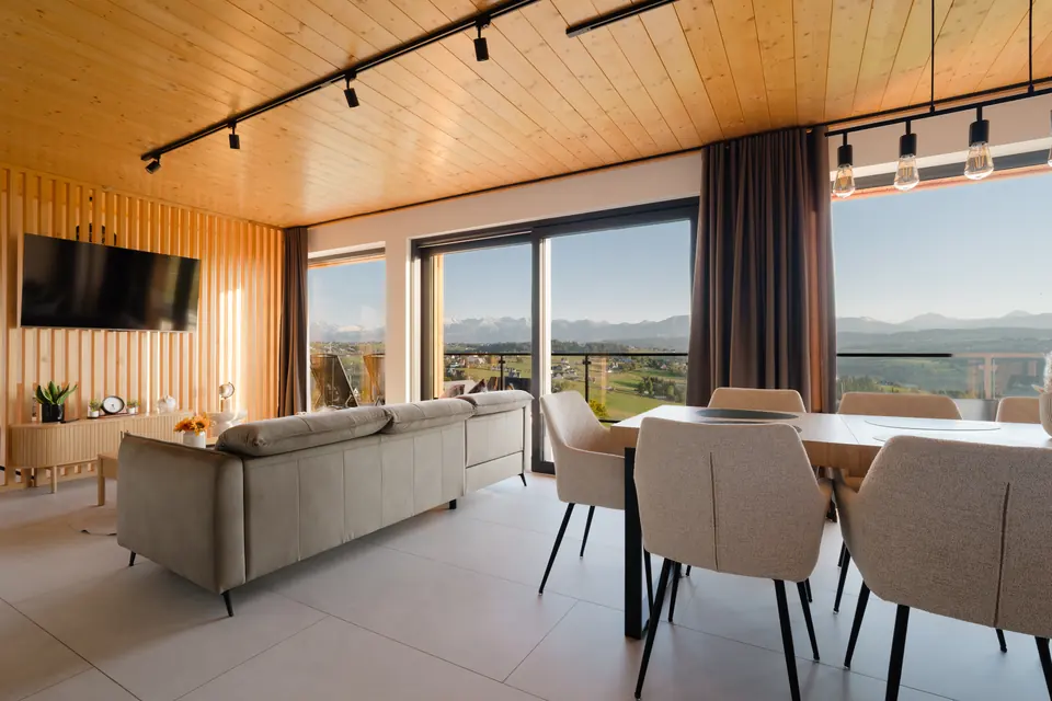 Salon i jadalnia przy przeszklonej ścianie z wyjściem na balkon